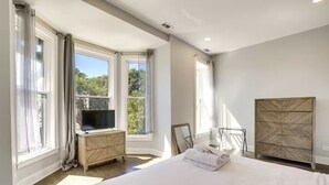 A bedroom with a large bed, a TV on a wooden dresser, and a wardrobe. - NEW! Stylish 3BD/2.5BTH w/parking! United Center! (Chicago)