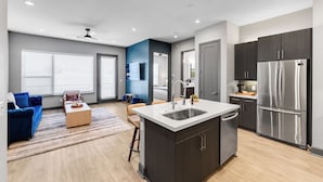 A modern kitchen with a central island, dark cabinetry, and stainless steel appliances.