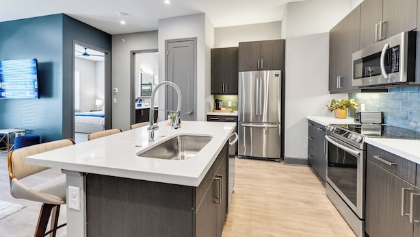 A modern kitchen with a central island, stainless steel appliances, and a blue accent wall.
