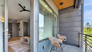 A modern interior with a balcony, wicker chairs, and a ceiling fan.