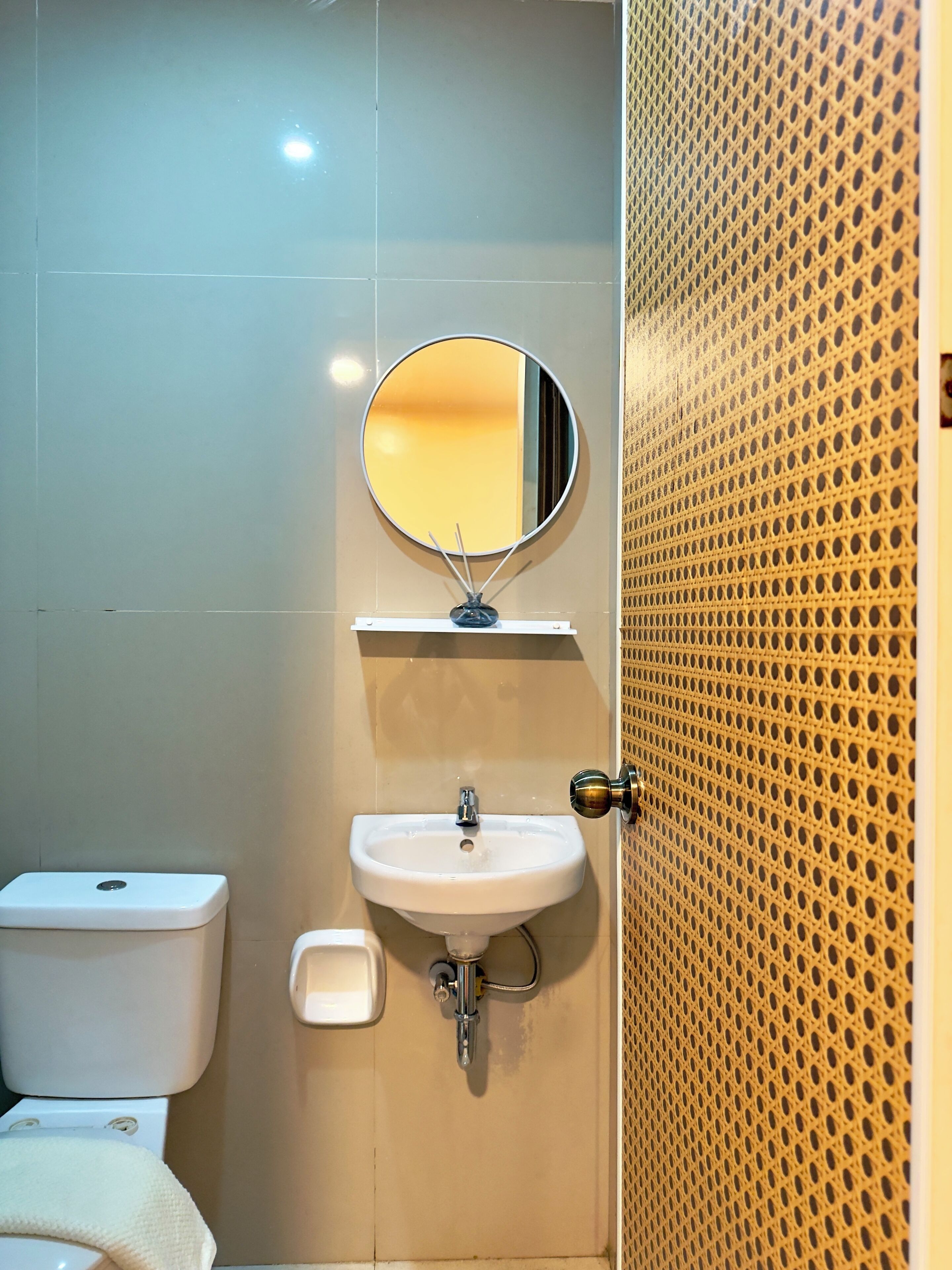 Een badkamer met toilet, wastafel en spiegel.