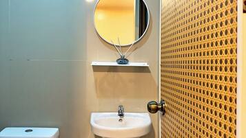 Een badkamer met toilet, wastafel en spiegel.