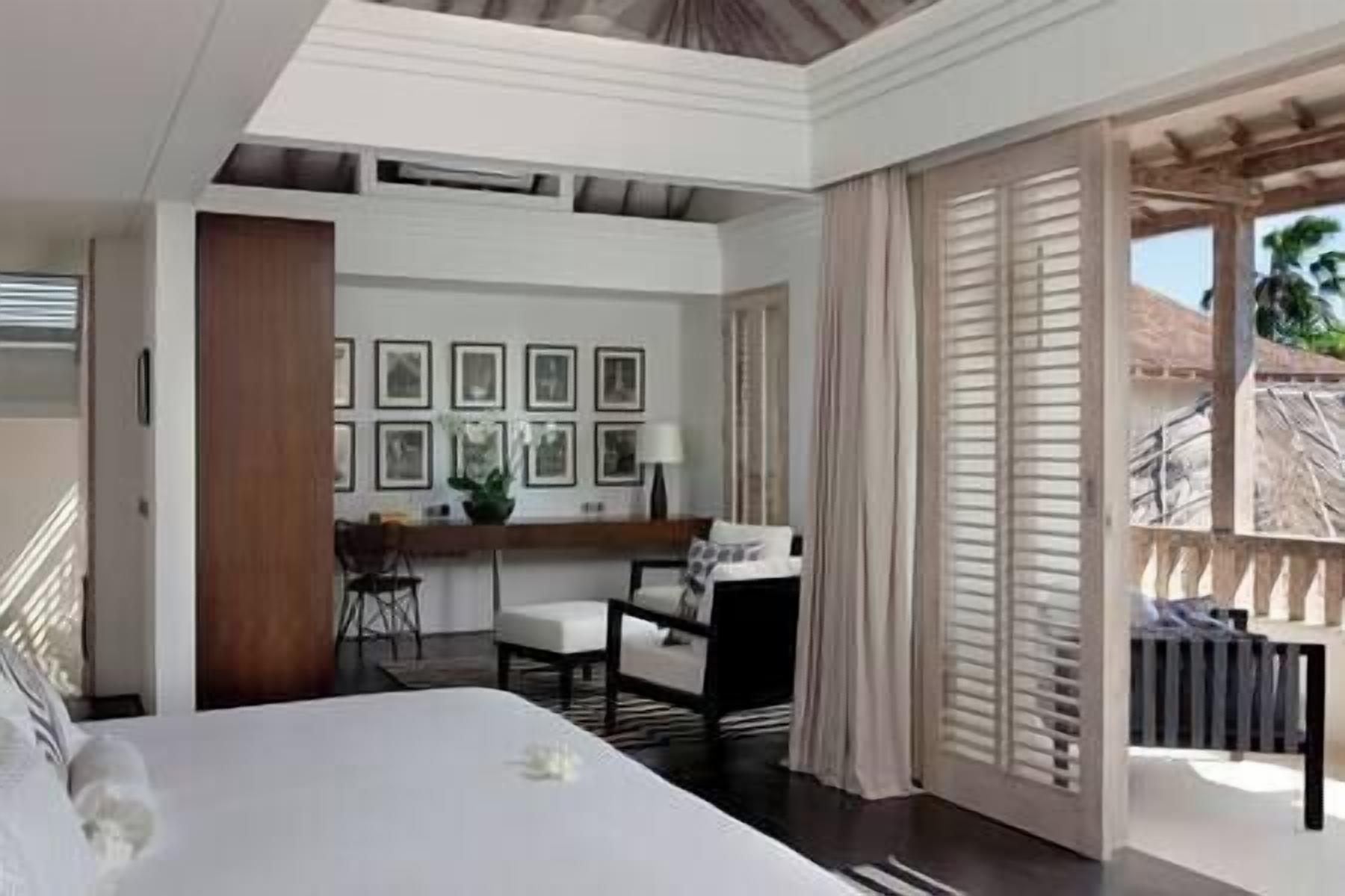 Habitación de hotel con cama, escritorio y silla, ventana con persianas y vistas al exterior.