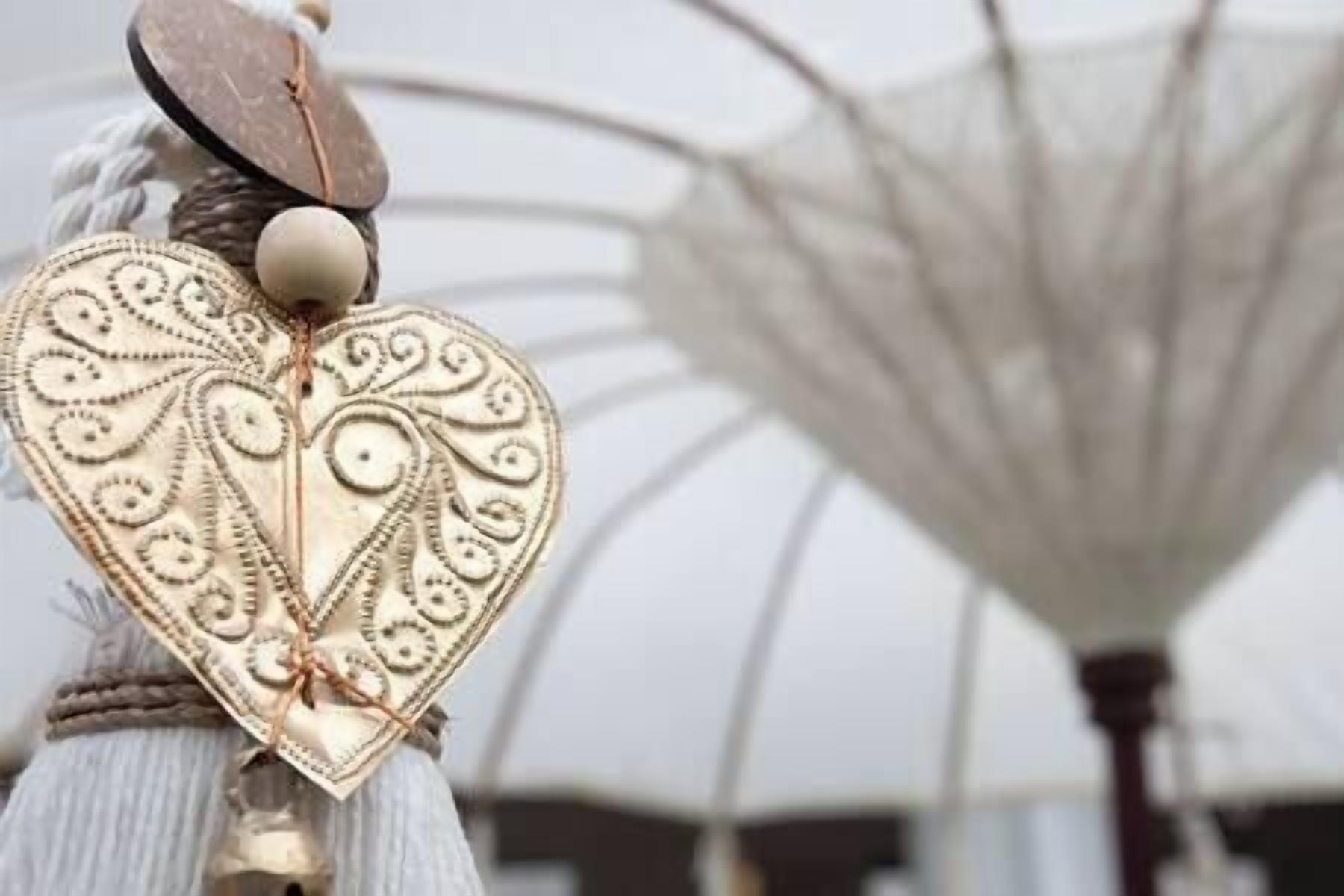 Un adorno con forma de corazón y diseños intrincados, sujeto a una estructura de tela blanca.
