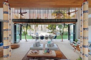 A modern outdoor seating area with a wooden table and chairs, surrounded by tall bamboo screens.