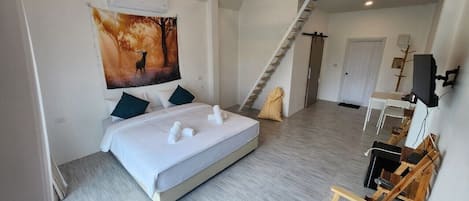 Un dormitorio moderno con una cama grande, un cuadro de un ciervo, una escalera y un escritorio con una computadora.