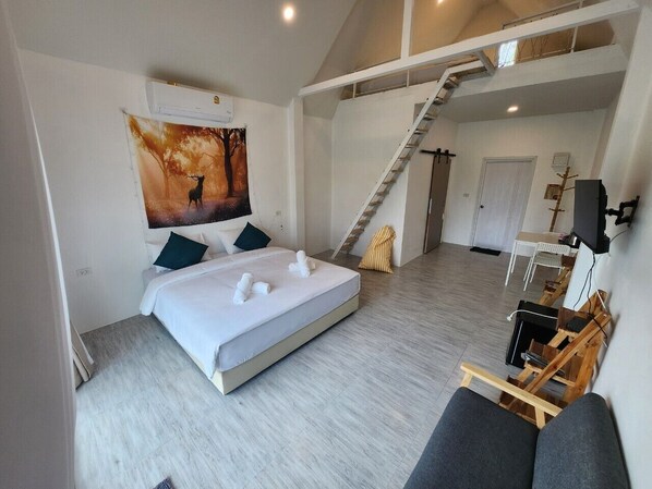 A modern bedroom with a large bed, a painting of a deer, a staircase, and a desk with a computer. - Casa Camp (Khao Kho)