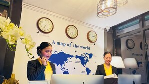A reception desk with clocks, a world map, and a sign indicating check-in and check-out times. - Sukhavati Inn (Baguio)