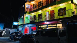 A multi-story building with balconies and a parking area in front. - Sukhavati Inn (Baguio)