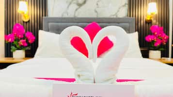 A hotel room with a bed, a heart-shaped towel decoration, and a sign indicating it is a guest room.