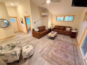 A spacious living room with two brown sofas, a patterned rug, and a wooden floor.