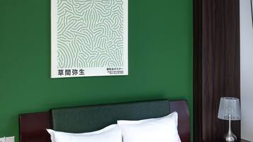 A hotel room with a bed, a nightstand, a lamp, and a poster on the wall.