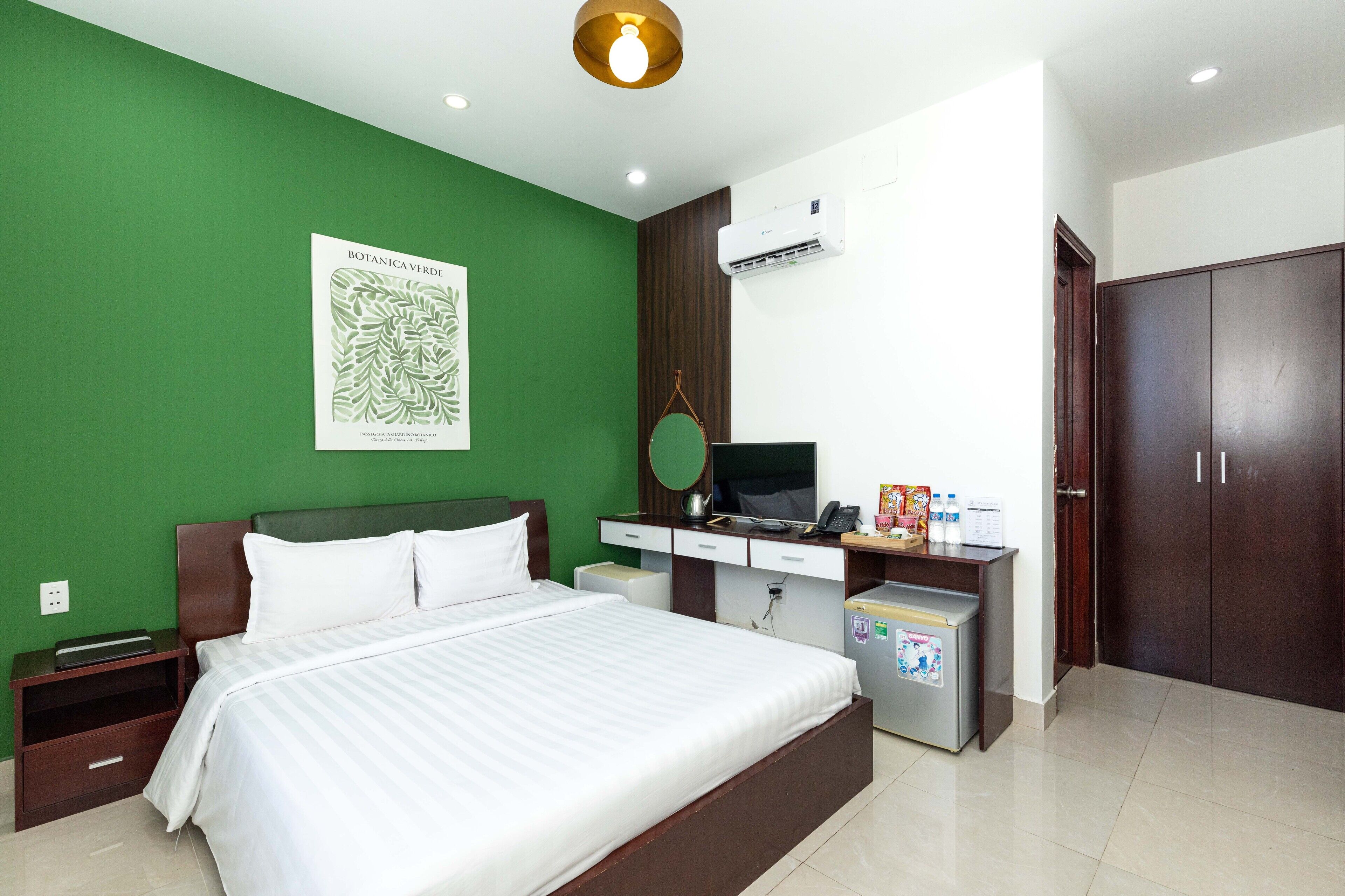 Habitación de hotel con cama, escritorio, televisor, minibar y armario.
