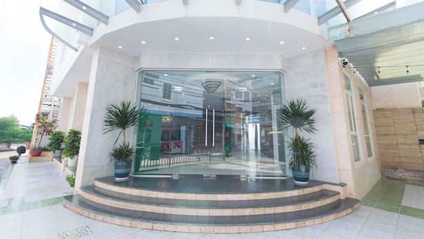 A modern building entrance with a glass facade, a central staircase, and potted plants. - Happy Home Boutique Hotel Vung Tau (Ho Chi Minh City)
