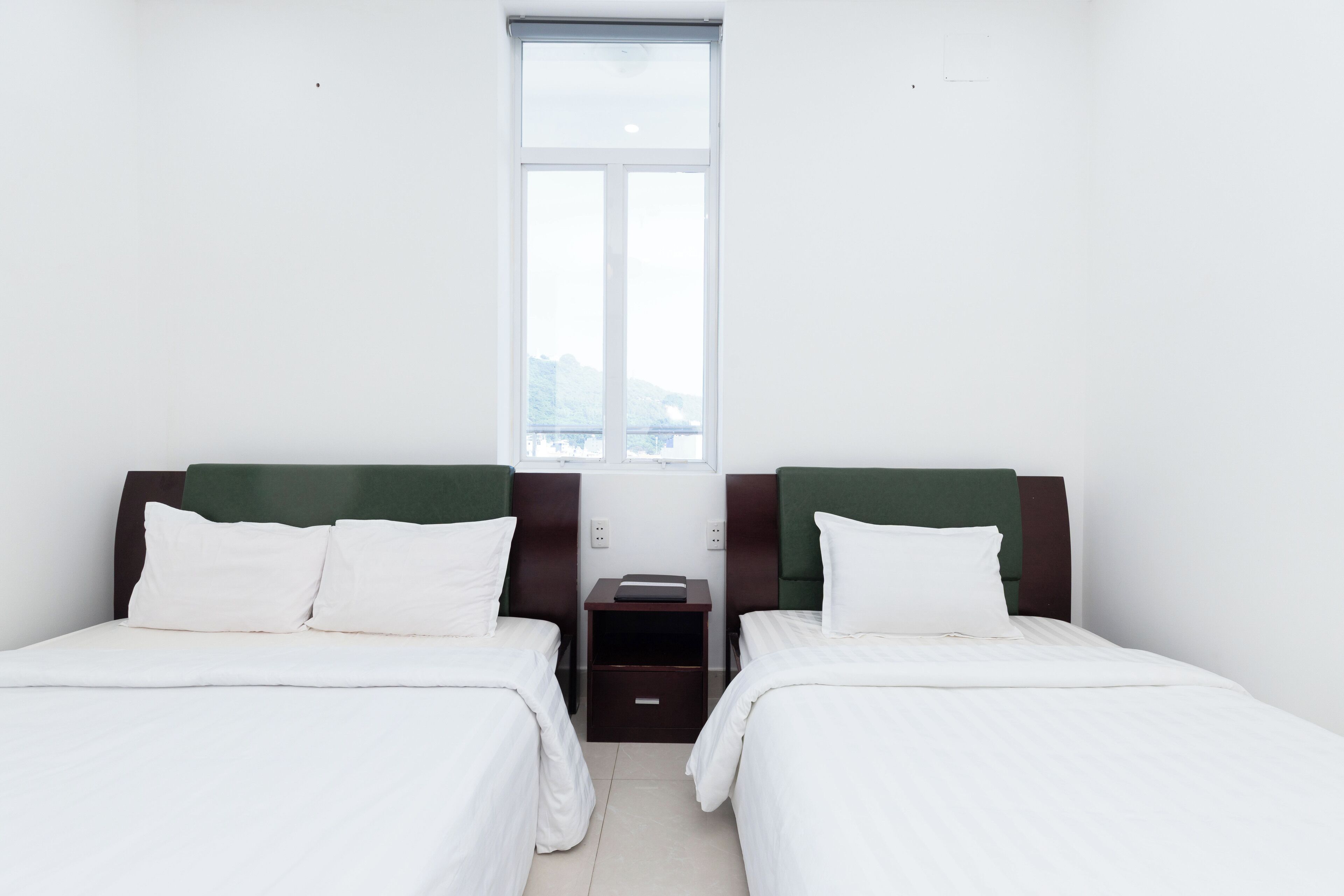 A room with two beds, a small table, and a window.
