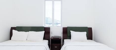 A room with two beds, a small table, and a window.
