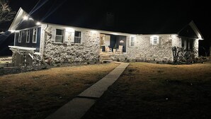 A stone house with a porch, a pathway leading to the entrance, and a small garden area.
