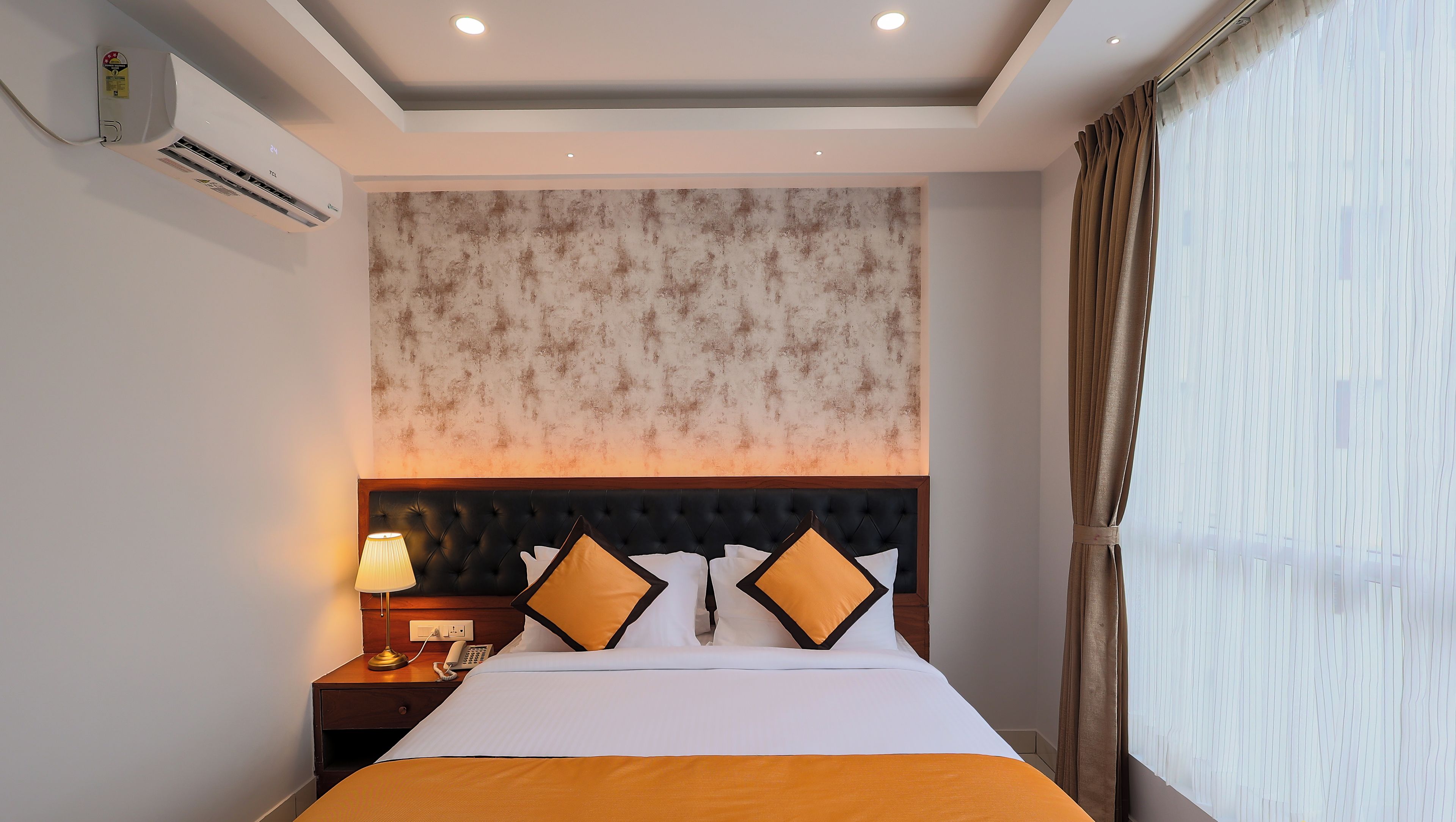Ein Hotelzimmer mit einem Bett, Nachttisch, Lampe und Klimaanlage.