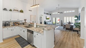 A spacious kitchen with white cabinetry, granite countertops, and a central island. - P83/PeoriaSportsCmplex/155 INCH SCREEN 4KHD THEATER/HEATEDPool/PuttingGreenOasis (Peoria)