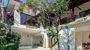 Une maison moderne à deux étages, dotée d’un patio couvert, d’un petit jardin et d’un escalier apparent.