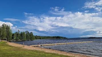 Vista de un lago con un muelle que se adentra en el agua, rodeado de zonas verdes y árboles densos.