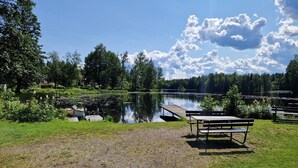 A lakeside park with a wooden bench, a dock, and a boat. - 4 Star Holiday Home in Torsaker (Torsåker)