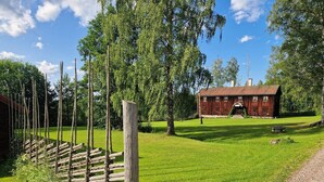 A rustic wooden cabin with a metal roof, surrounded by a well-maintained lawn and tall trees. - 4 Star Holiday Home in Torsaker (Torsåker)