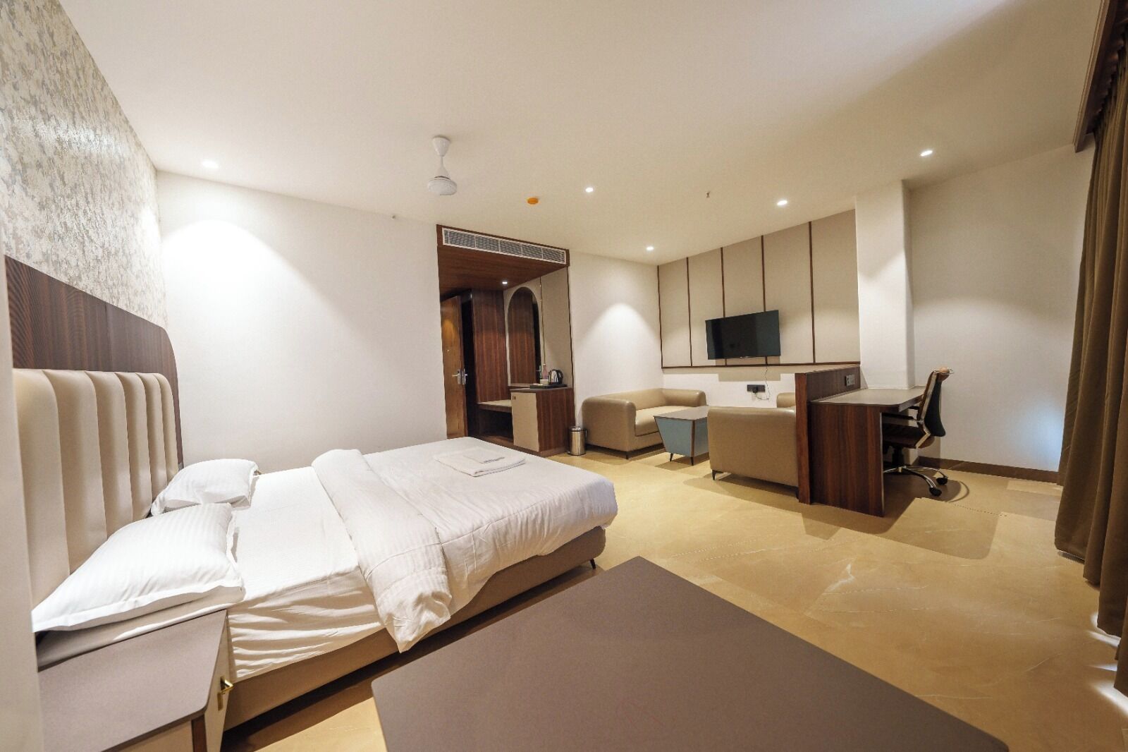 Une chambre d’hôtel moderne équipée d’un lit, d’un bureau, d’une chaise, d’une télévision et d’une salle de bain.