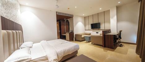 Une chambre d’hôtel moderne équipée d’un lit, d’un bureau, d’une chaise, d’une télévision et d’une salle de bain.