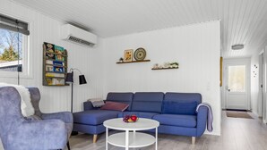 Un salon avec un canapé bleu, une table basse ronde blanche et un fauteuil gris.
