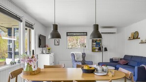 Un salon moderne avec une table à manger en bois, un canapé bleu et deux lampes suspendues.