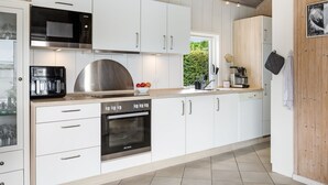 A modern kitchen with white cabinets, stainless steel appliances, and a wooden ceiling. - "Arnia" - 250m from the sea by Interhome (Hejls)