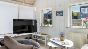 A modern living room with a flat-screen TV, a sofa, a coffee table, and potted plants. - "Arnia" - 250m from the sea by Interhome (Hejls)