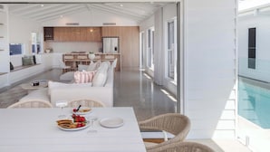 Un interior moderno con comedor, cocina y vista a una piscina.