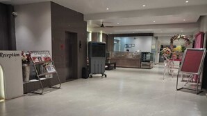 A reception area with a reception desk, a glass partition, and a sign that reads "Reception". - Hotel Downtown (Bilaspur)