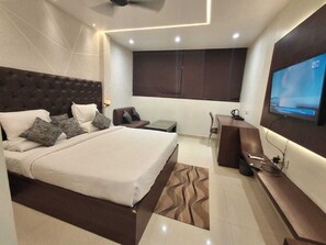 Ein modernes Hotelzimmer mit einem großen Bett, einem Schreibtisch, einem Flachbildfernseher und einem Deckenventilator.