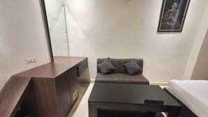 A compact living space with a sofa, a coffee table, a bed, and a wooden cabinet. - Hotel Downtown (Bilaspur)