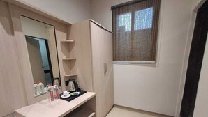 A compact bedroom with a bed, a bedside table with a lamp, a wardrobe, and a window with blinds. - Hotel Downtown (Bilaspur)