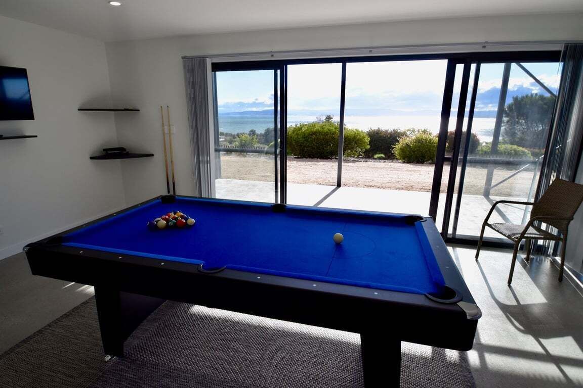 Une table de billard avec des billes, un téléviseur et une vue sur l’extérieur.