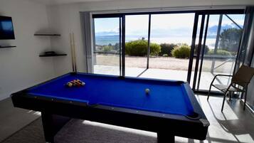 A pool table with balls, a television, and a view of the outdoors.