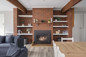 Una sala de estar con chimenea de ladrillo, estanterías blancas y un sofá gris.