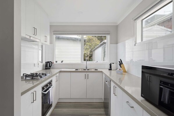 Una cocina moderna con armarios blancos, un lavamanos de acero inoxidable y un horno.