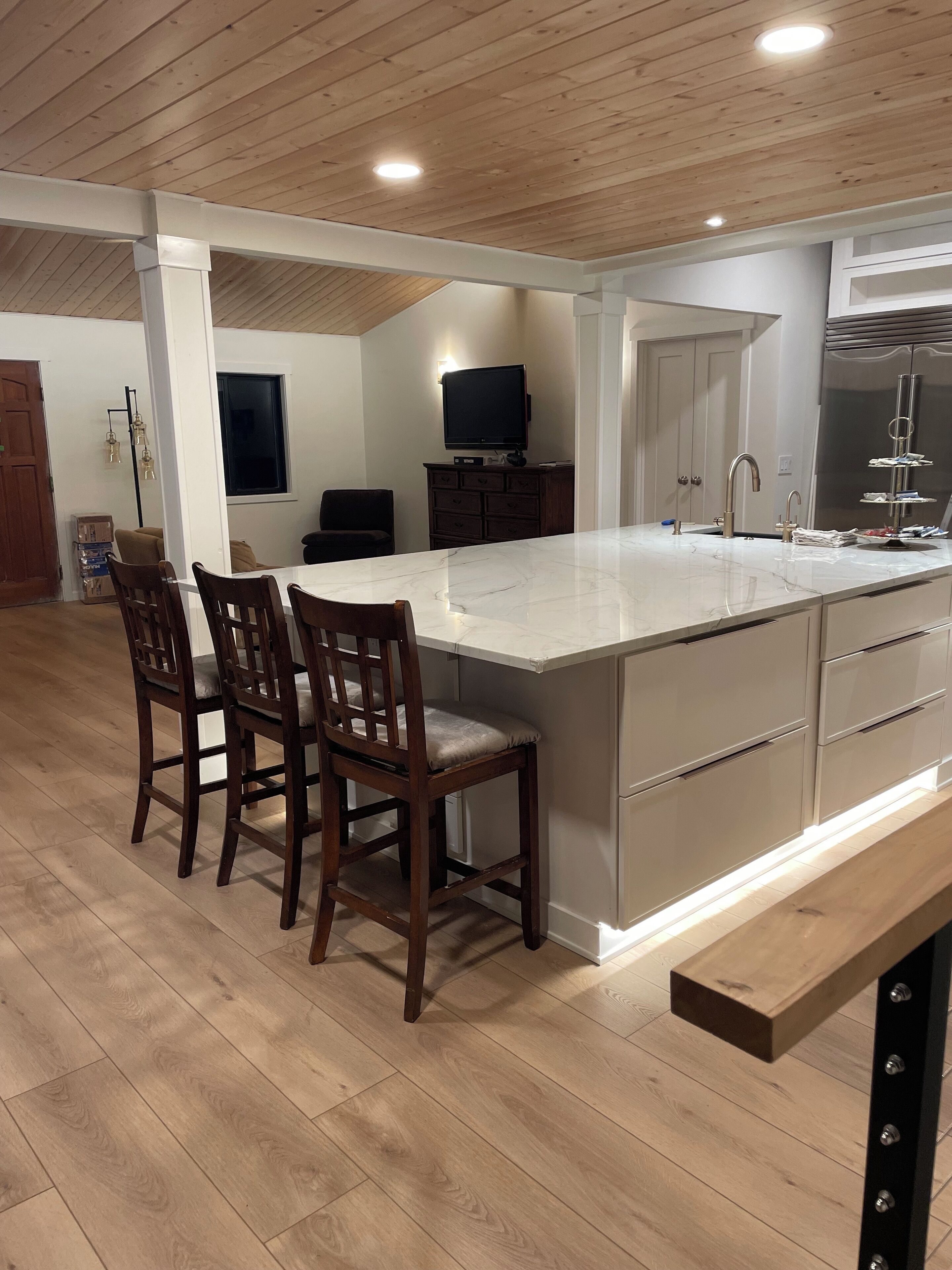 Une cuisine moderne dotée d’un grand îlot central, de chaises en bois et d’un four encastré.