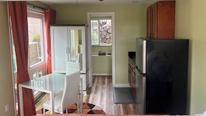 A compact kitchen with a refrigerator, a dining table with chairs, and a ceiling fan. - Kona Nook - Cozy Studio with Island Warmth (Kailua-Kona)