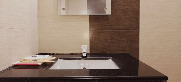 Un baño con un lavabo negro, un espejo y un perchero para toallas.