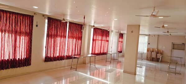 A spacious hotel room with large windows, ceiling fans, and a tiled floor. - Hotel Diamond (Kumbakonam)