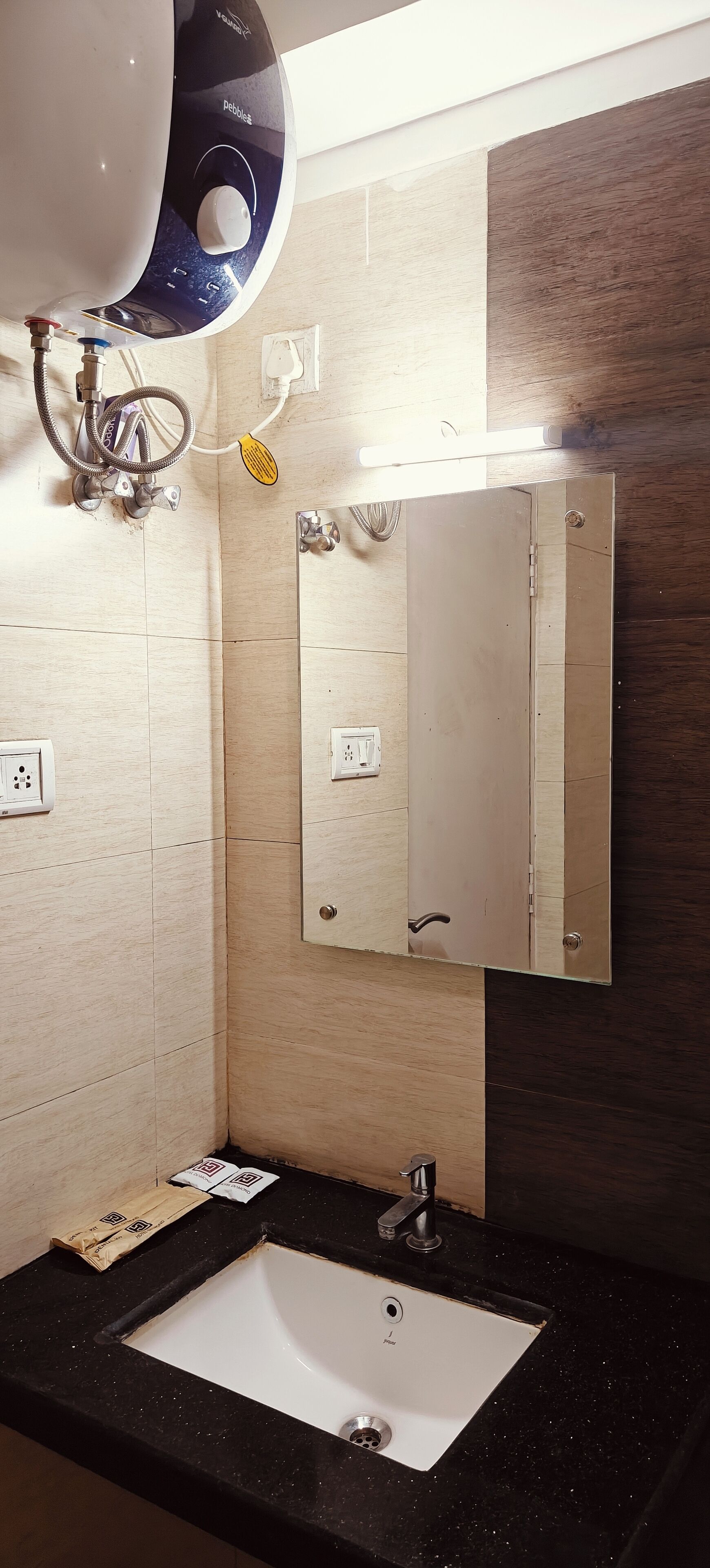 Un baño con un lavabo blanco, un espejo y un cabezal de ducha.
