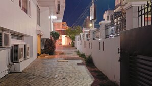 Uma passagem estreita com edifícios de ambos os lados, aparelhos de ar condicionado e uma entrada gradeada.