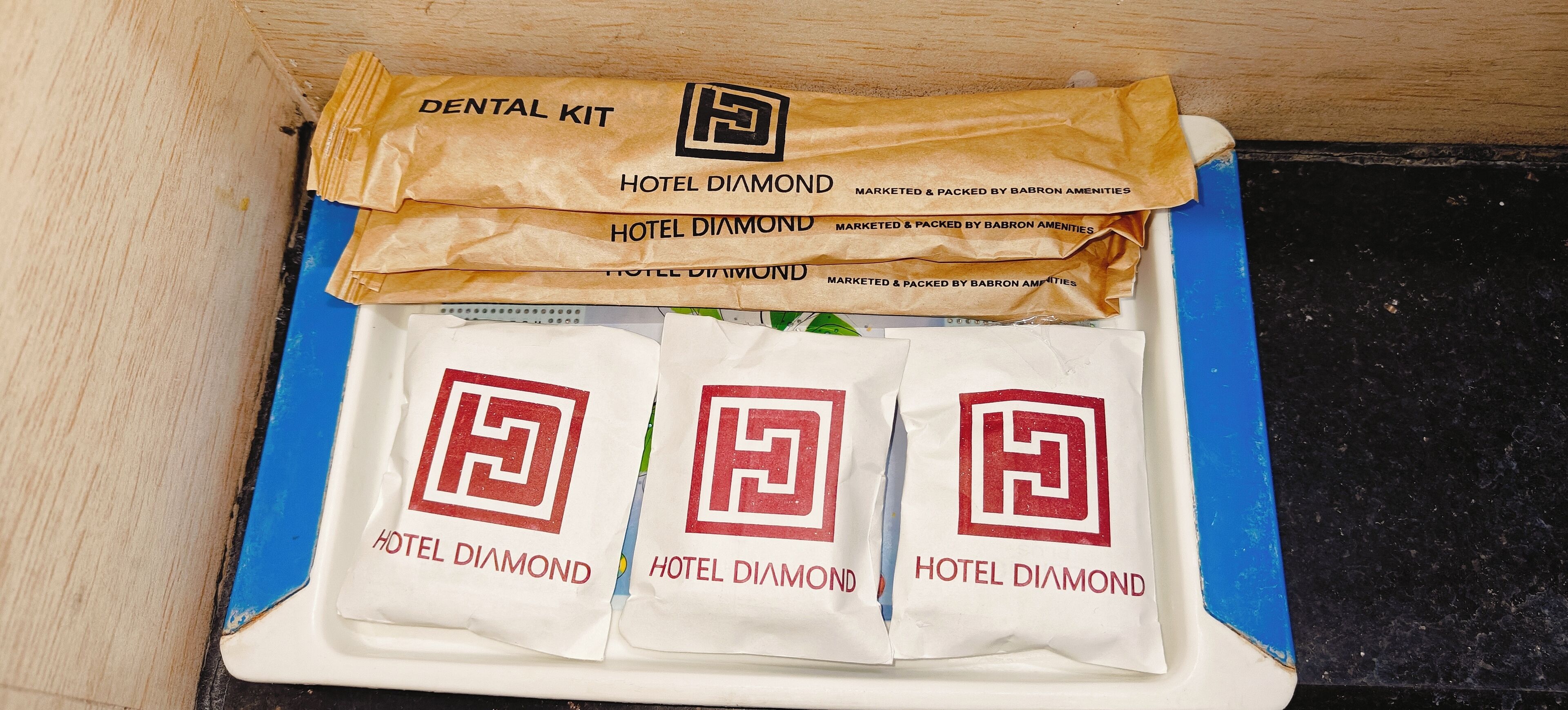 Un kit dental y tres bolsas de hotel con un logotipo, todo sobre una superficie azul.