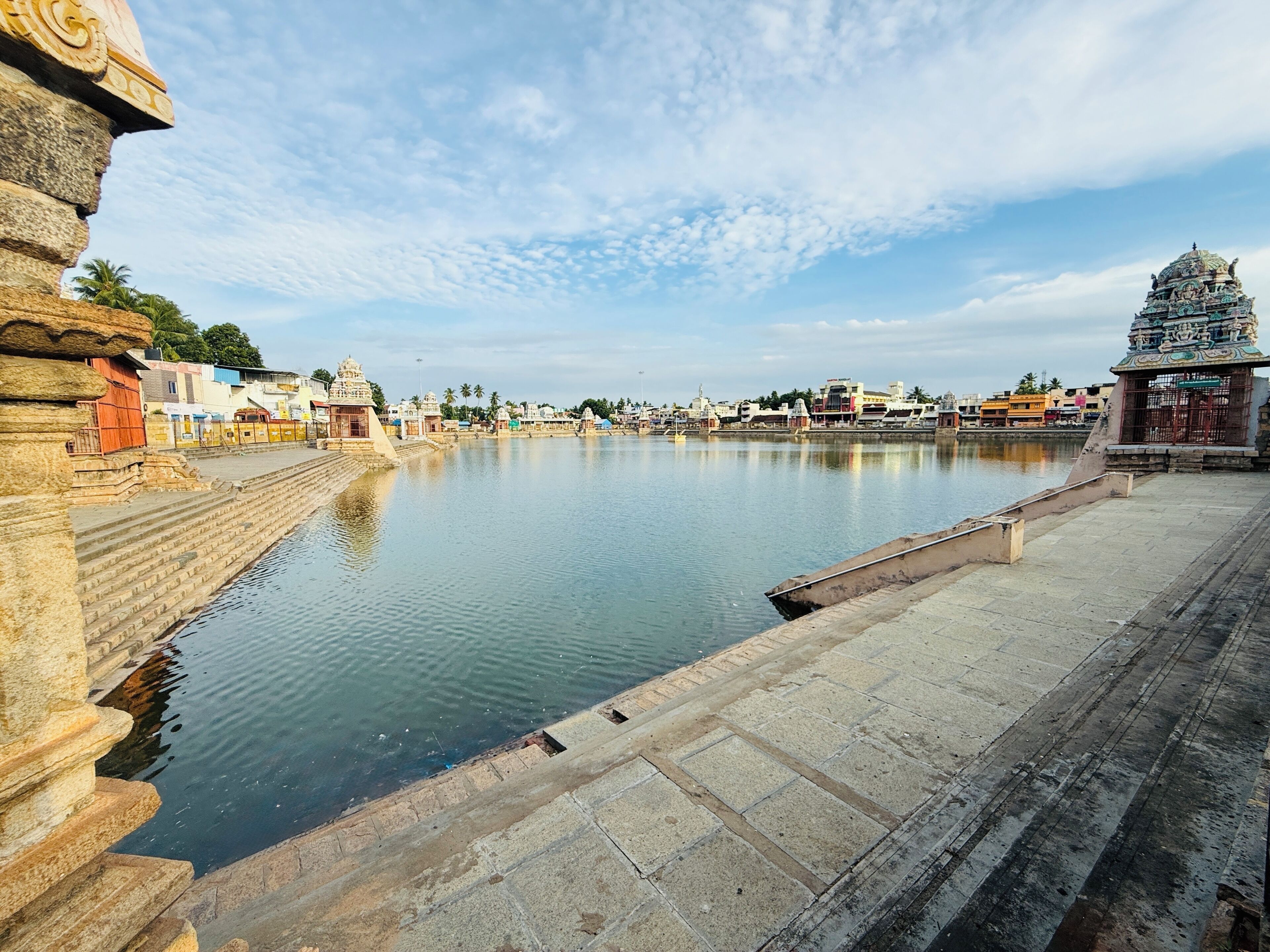 Vista sul fiume con gradini in pietra che scendono nell'acqua, un tempio con elaborate decorazioni e un cielo sereno.